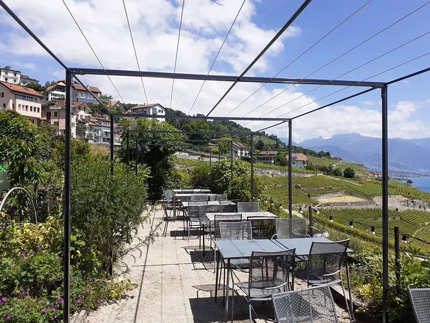 Pergola métallique au-dessus d'une terrasse dans les vignes, vue sur le lac