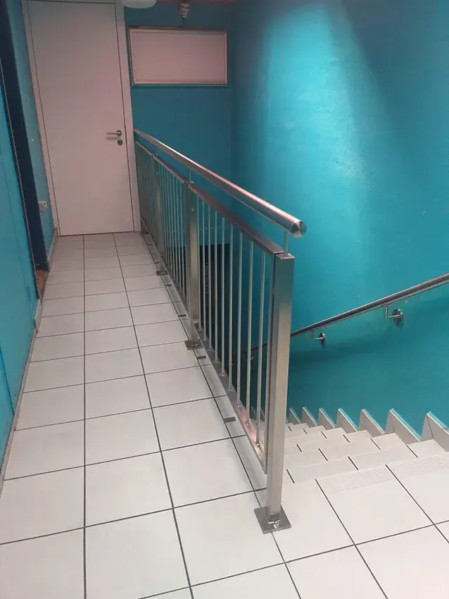Balustrade en inox à barreaux verticaux en haut d'une cage d'escalier