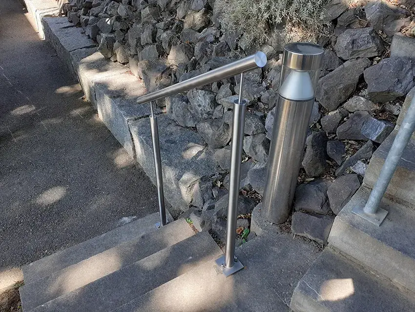Main courante en inox le long d'un escalier extérieur bordé de rochers