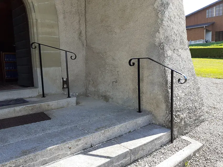 Mains courantes en fer forgé noir de part et d'autre d'une entrée, vue de face