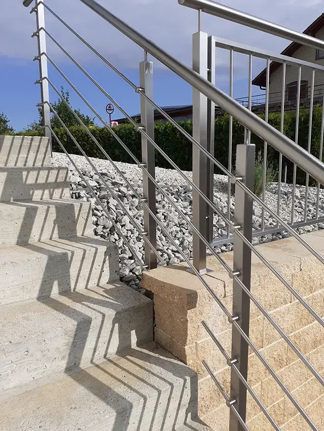 Garde-corps en inox à barreaux le long d'un escalier extérieur en pierre