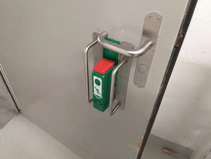 Poignée en inox à côté d'un boîtier d'ouverture de secours