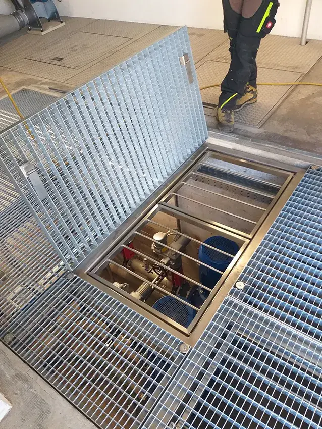 Trappe en caillebotis ouverte au-dessus d'une installation technique