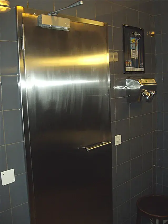 Porte habillée d'inox avec poignée et serrure, à côté d'un interphone